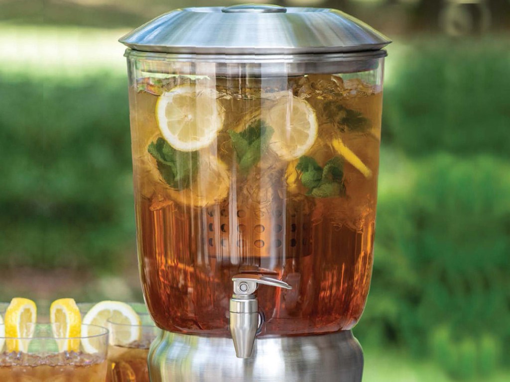 large chrome beverage infuser sitting next to glasses of iced tea and lemons