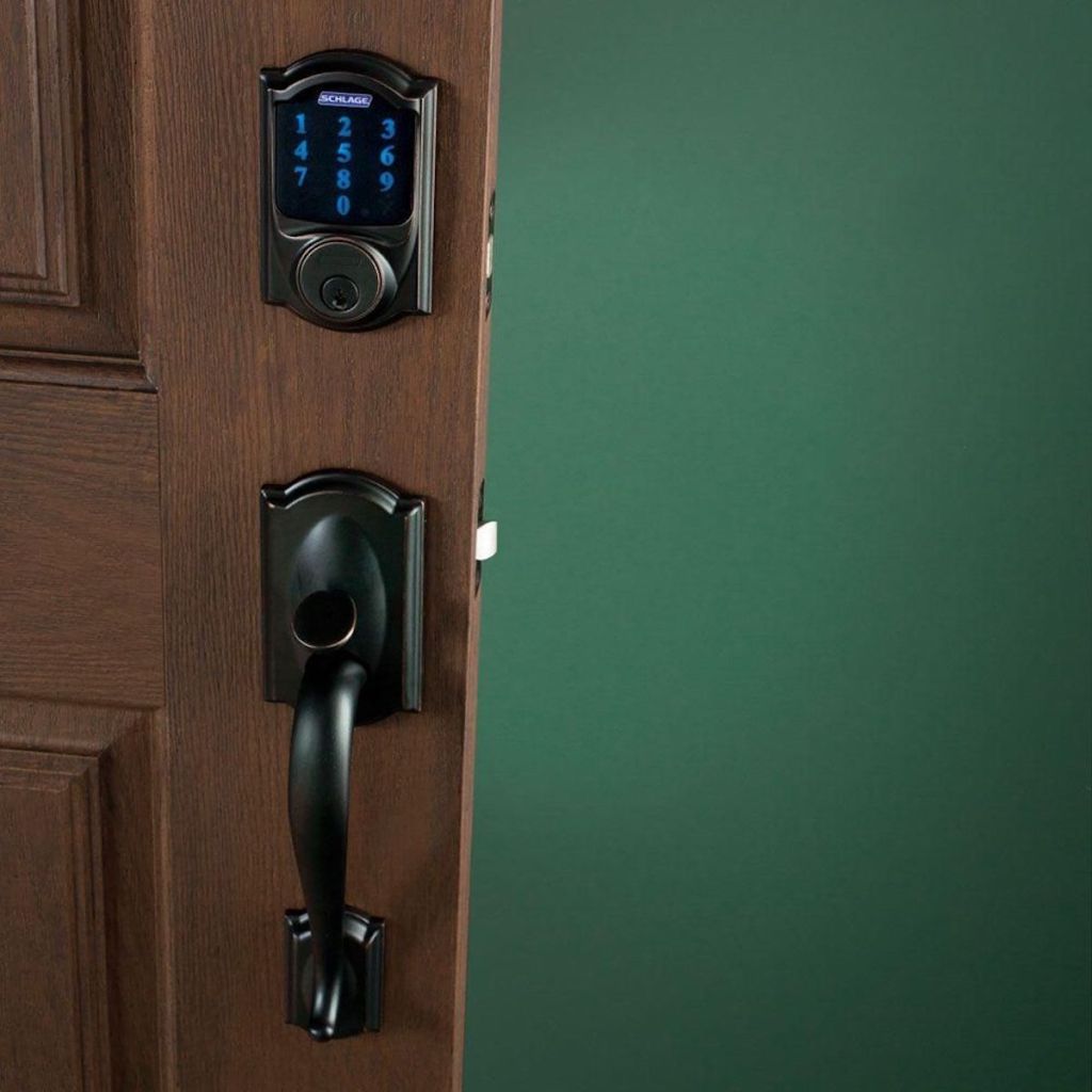 black schlage smart lock on brown door with green painted wall