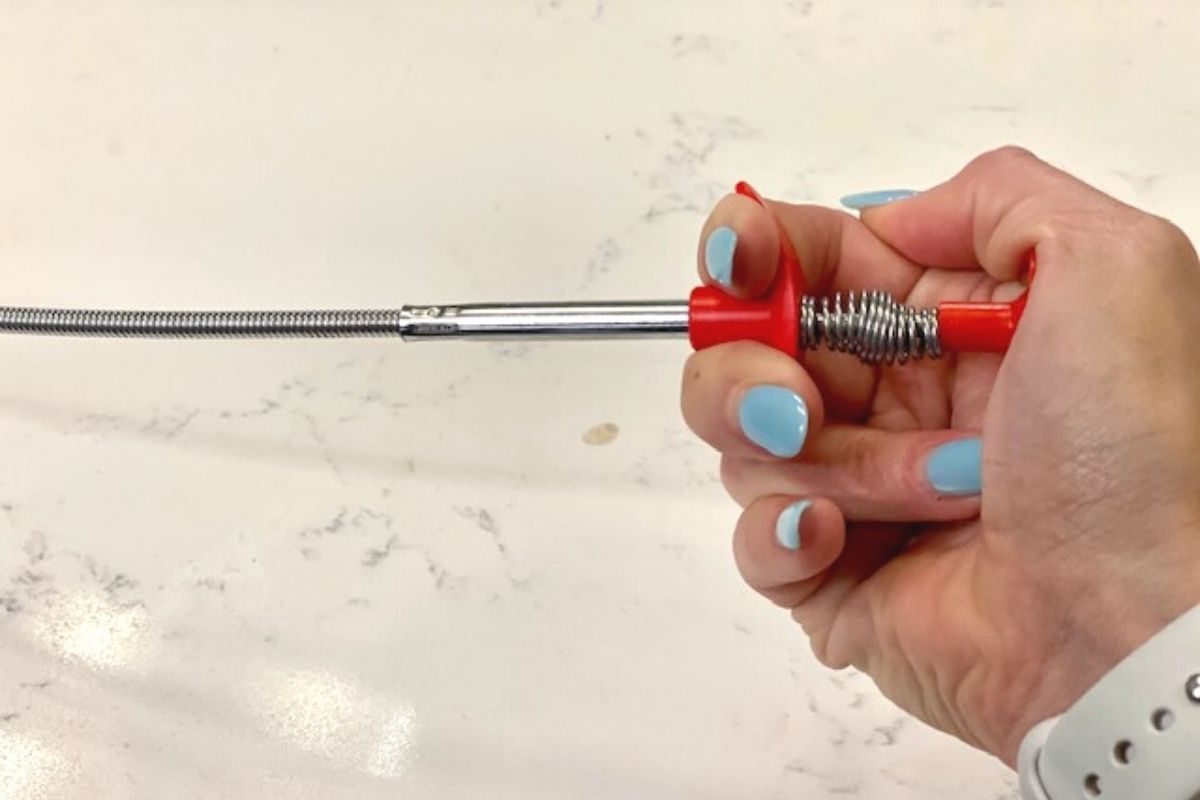 A hand pressing on a spring handle of a tool