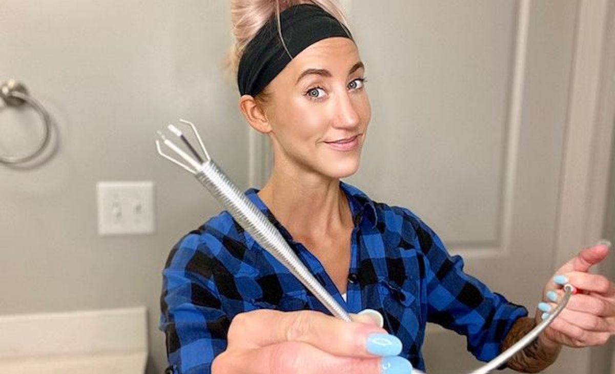 A woman holding a drain clog tool