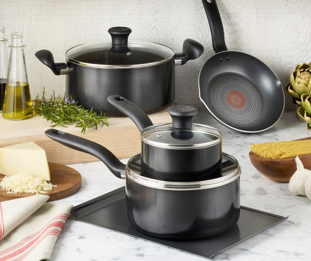 black t-fal cookware set on kitchen countertop near foods and cutting board