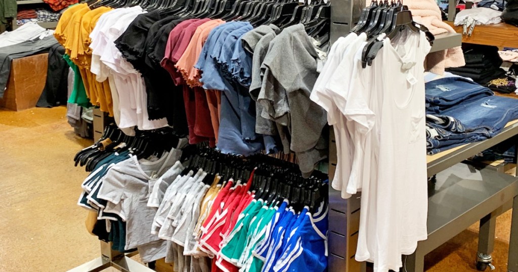 rack of girls shirts and shorts hanging on hangers inside Tillys store