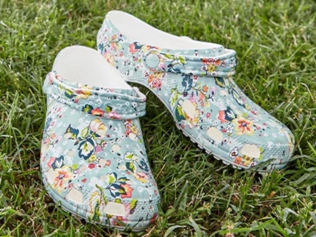 pair of floral print clogs resting on grass