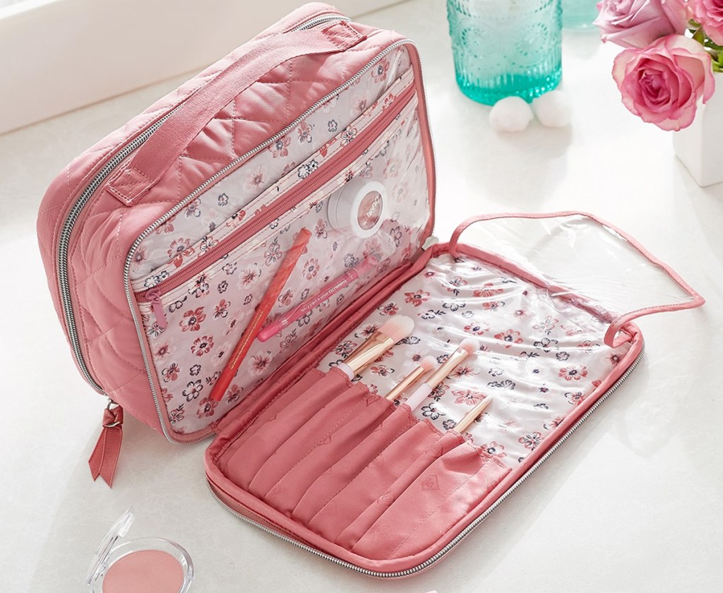 pink makeup case on bathroom counter with clear interior pockets