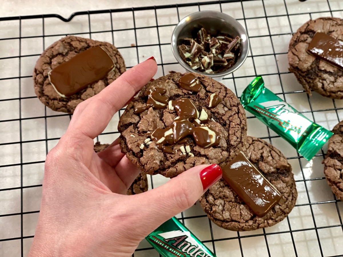 hand holding chocolate cookie in front of Andes candies