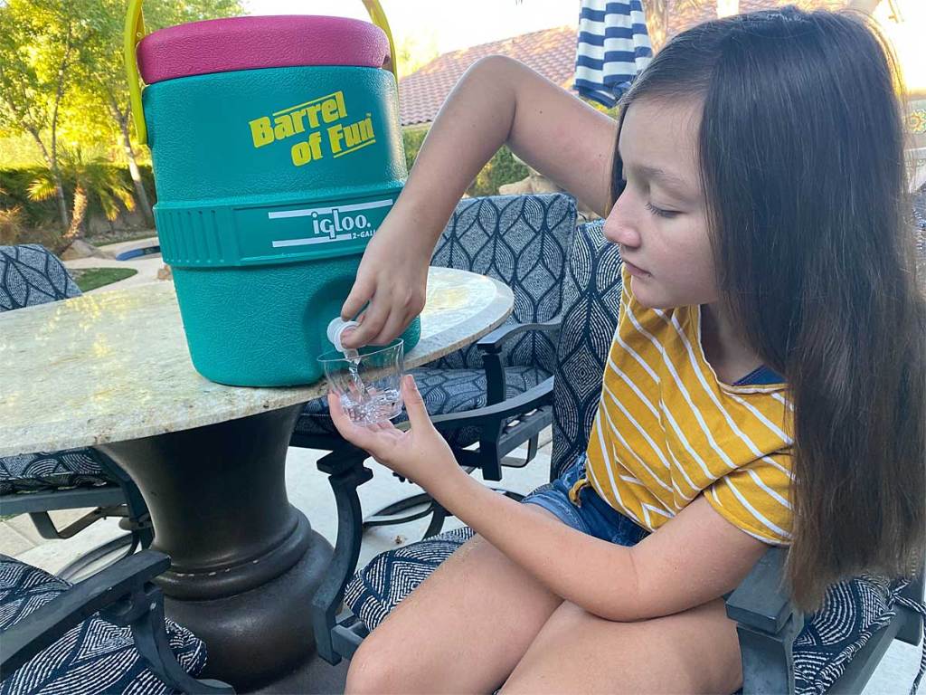 young girl pouring water out of cooler