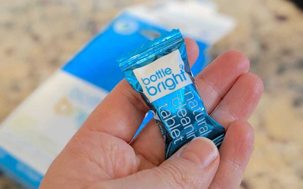 hand holding a blue bottle bright tablet