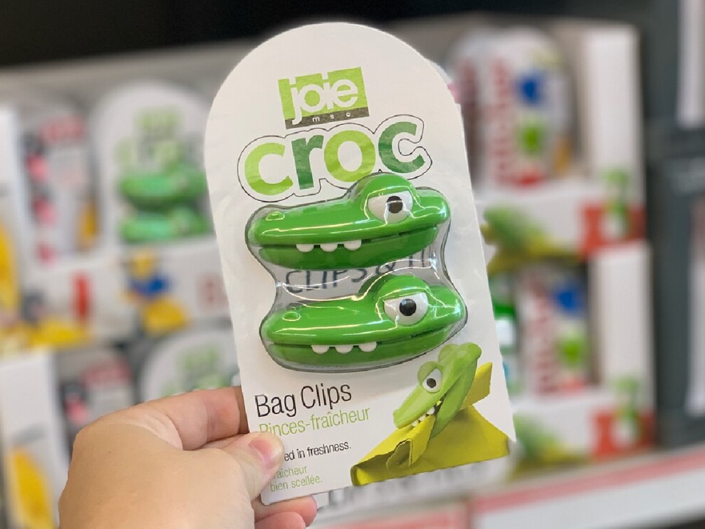 hand holding crocodile shaped bag clips in front of store display