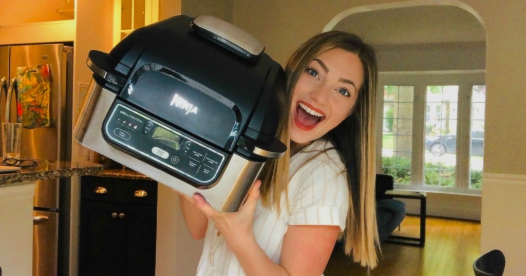 woman holding kitchen appliance with smile on her face