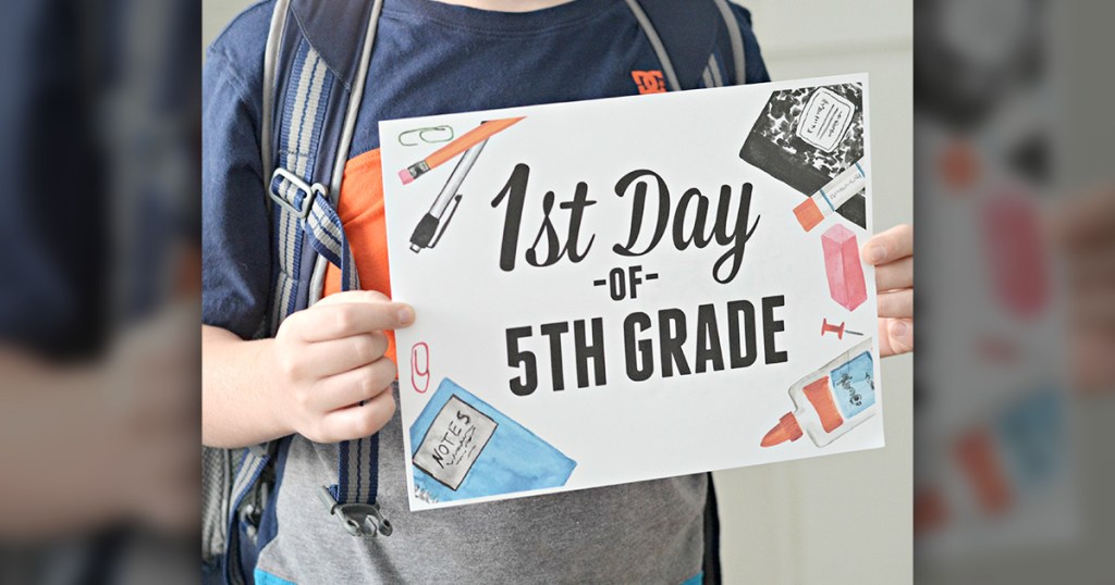 boy holding 1st day of school sign
