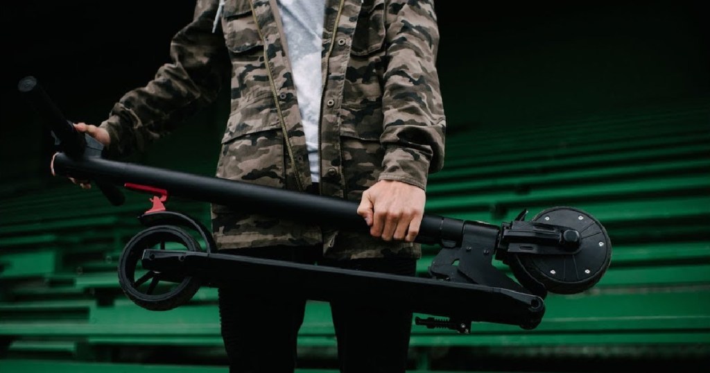 boy holding electric scooter folded up
