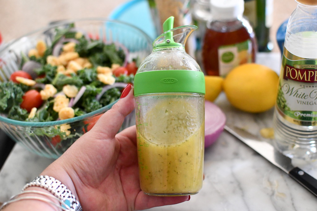 holding salad dressing shaker with salad in the background