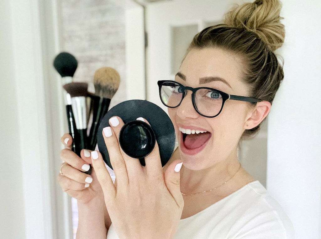 woman holding pop socket silicone mat and makeup brushes