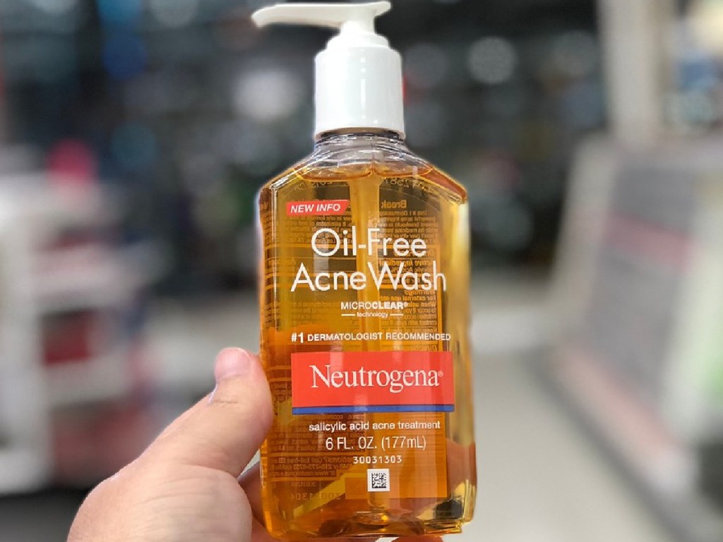 hand holding bottle of orange face cleaner