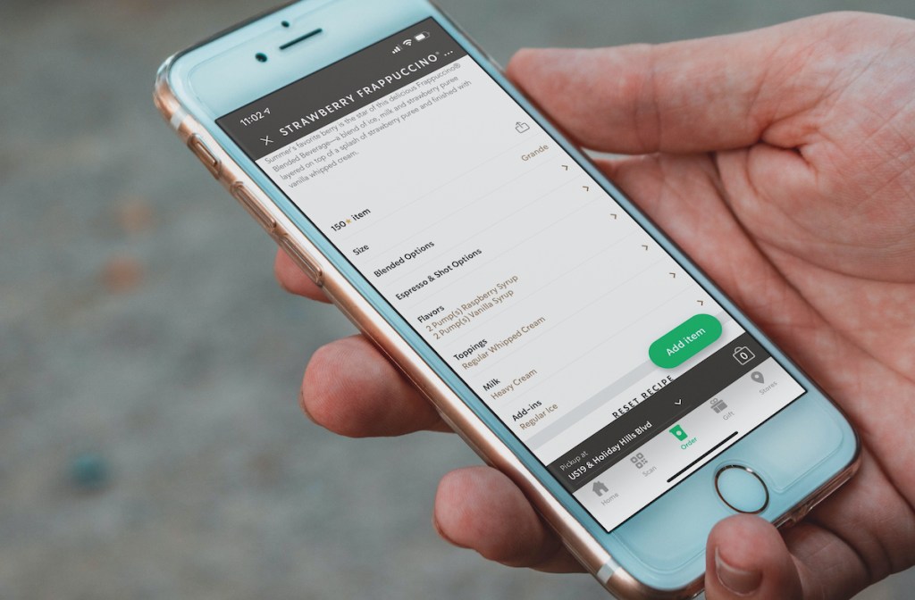 hand holding phone with starbucks skittles frappuccino order on screen