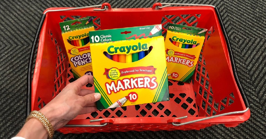 hand holding Crayola Markers in front of basket with other crayola items