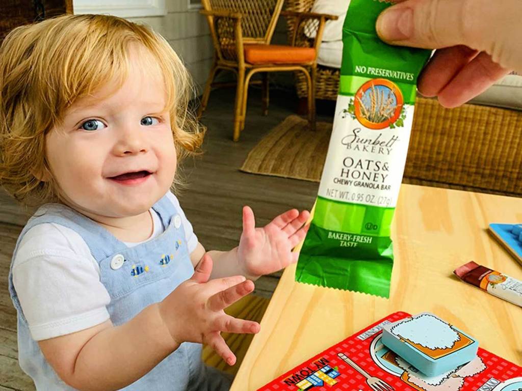 man handing granola bar to small child