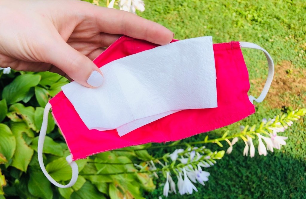 hand holding a pink mask with tissue inside to keep from fogging