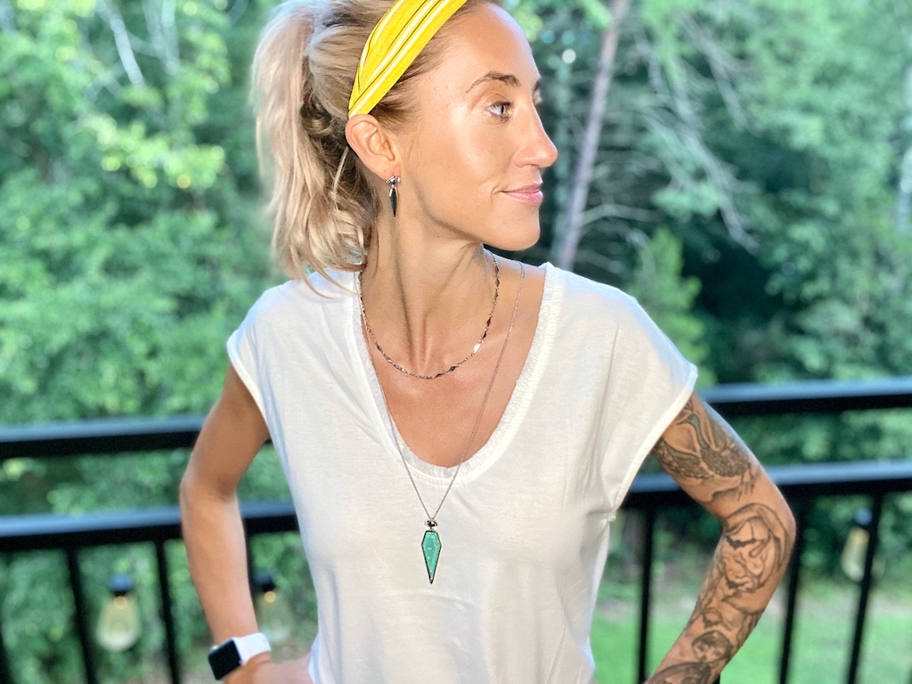 woman wearing 3 piece jewelry set, headband, and white tee