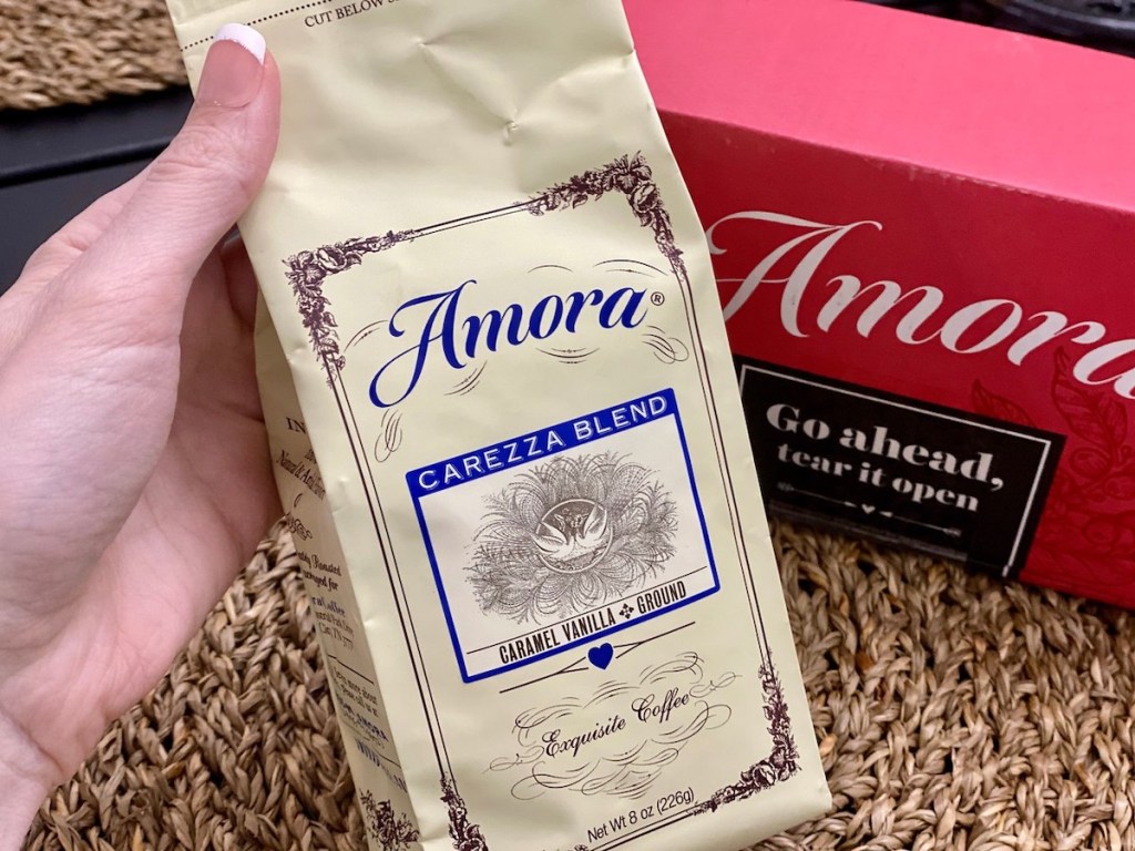 hand holding bag of amora with amora box in the background