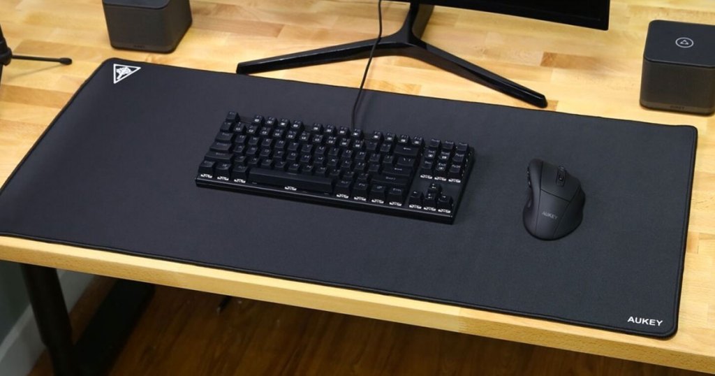 large black gaming keyboard under black keyboard and mouse on wood desk