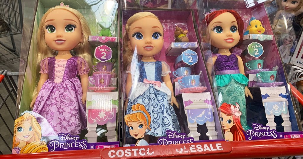 three Disney princess dolls in child seat area of Costco shopping cart