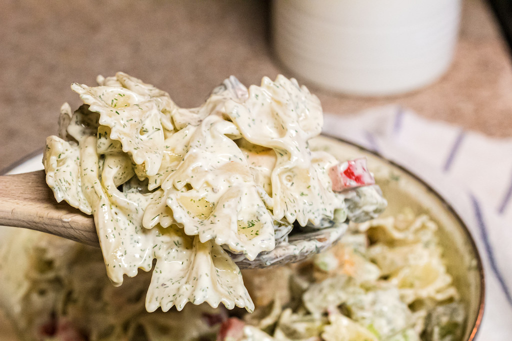 dill pickle pasta salad on wooden spoon