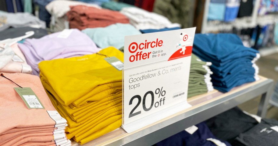 store display table full of folded men's basic tees with 20% off sale sign
