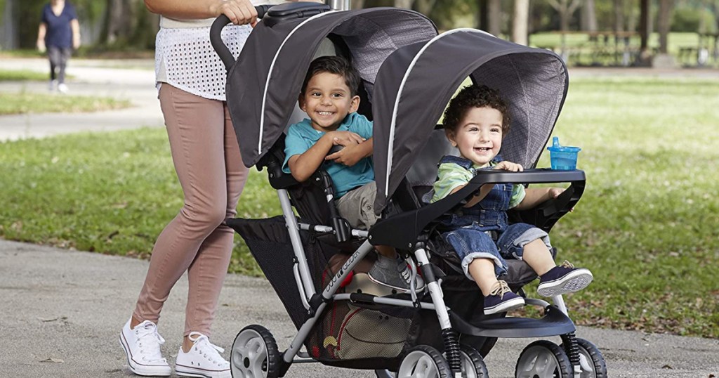 woman pushing two children in double stroller outside