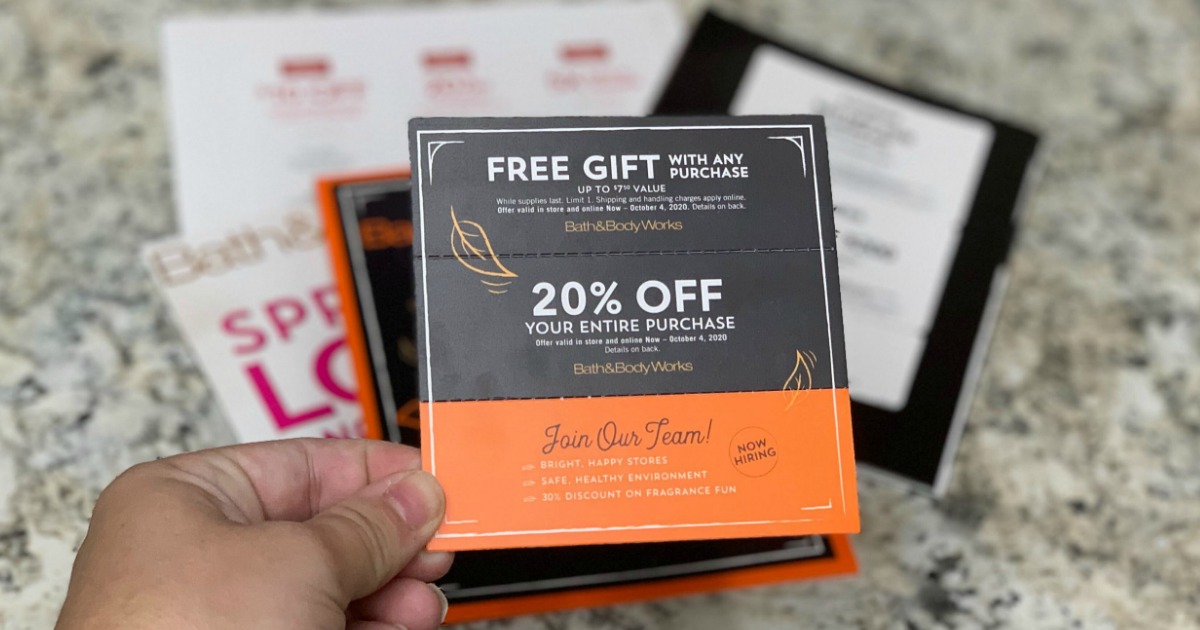 Woman's handing holding a store coupon near a counter full of additional store coupons