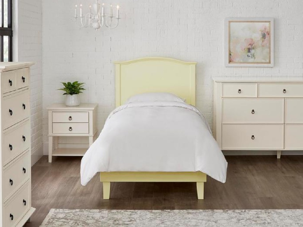 yellow twin bedding with a white blanket surrounded by white bedroom furniture