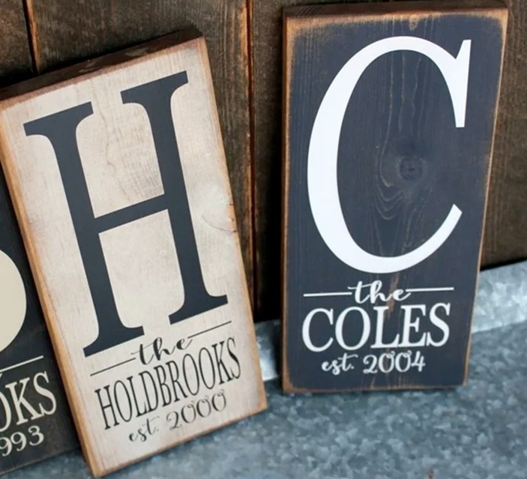 two wooden personalized signs with last names and years family was started