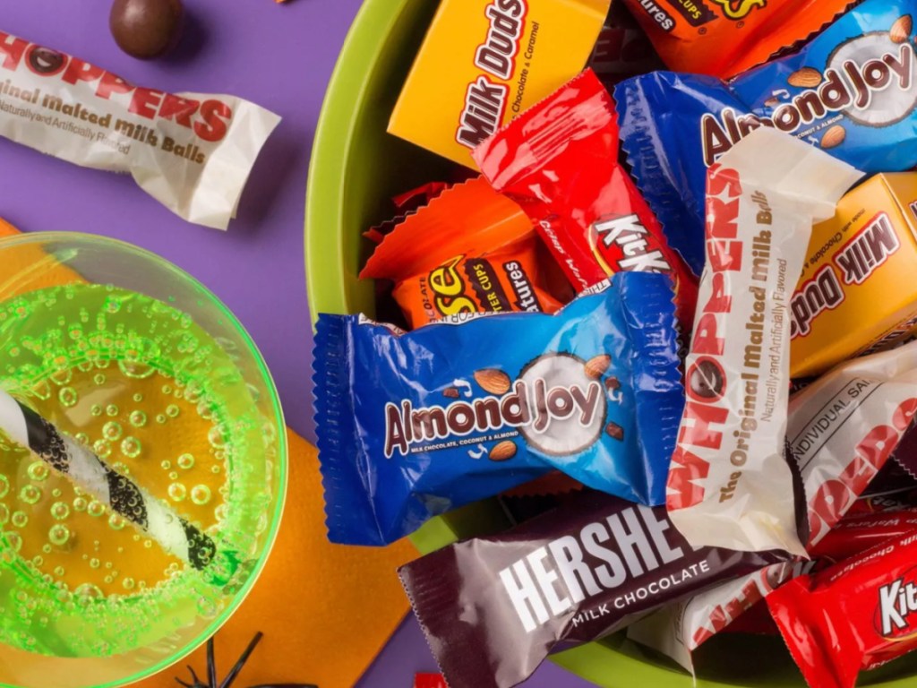 bowl os Halloween candy next to a green soda and black and white straw