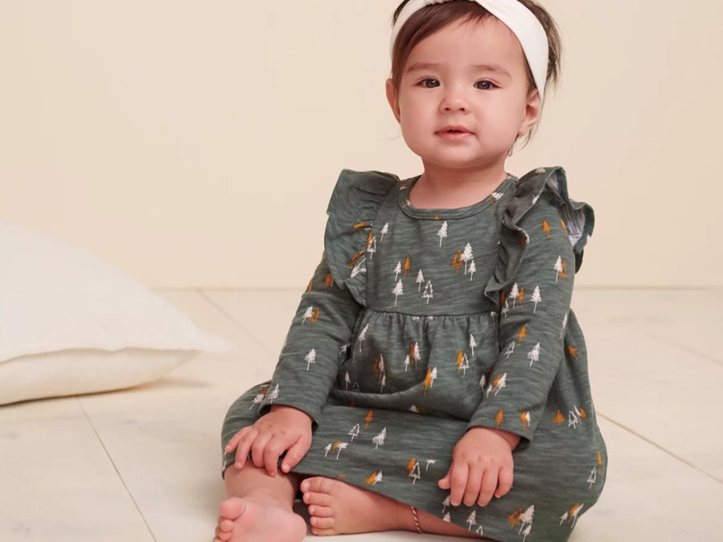 baby girl sitting on the floor wearing a cute fall dress and matching headband