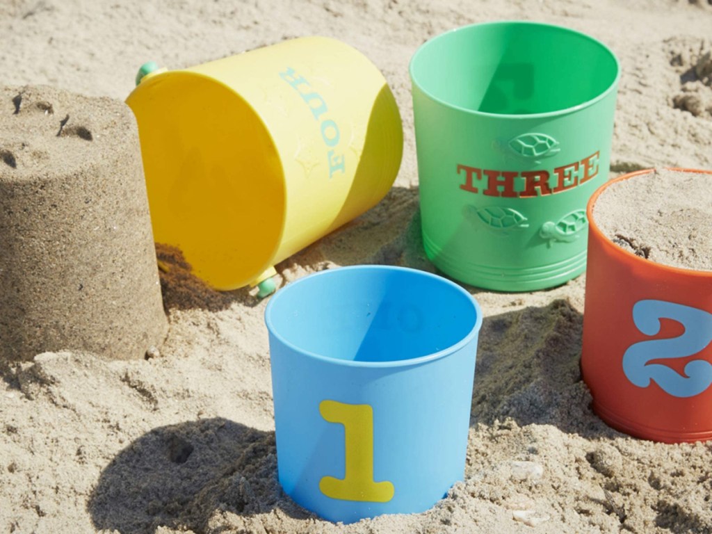 multi colored sand buckets numbered and sitting on a beach 