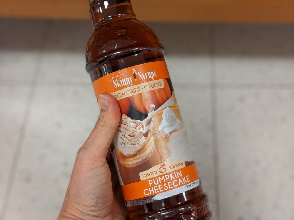 hand holding large bottle of pumpkin cheesecake sugar free syrup