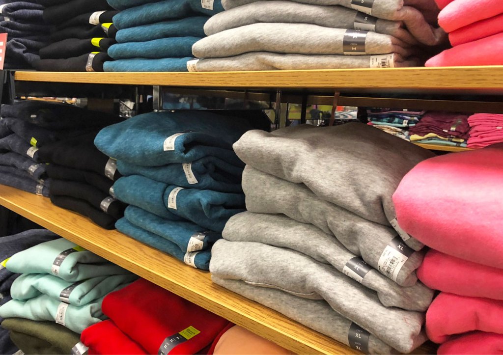 stacks of folded women's sweatshirts on wood display shelves