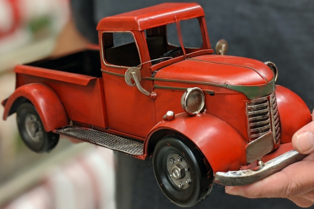 man holding vintage red truck decor