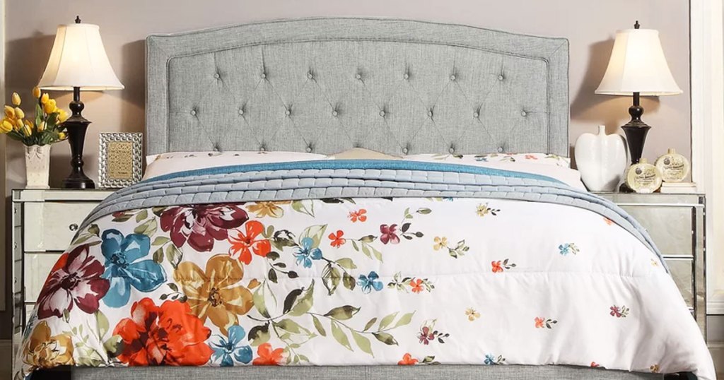 grey tuffed upholstered headboard on bed with floral print bedspread