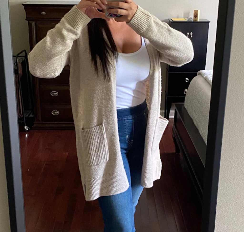 woman taking selfie in mirror wearing beige cardigan
