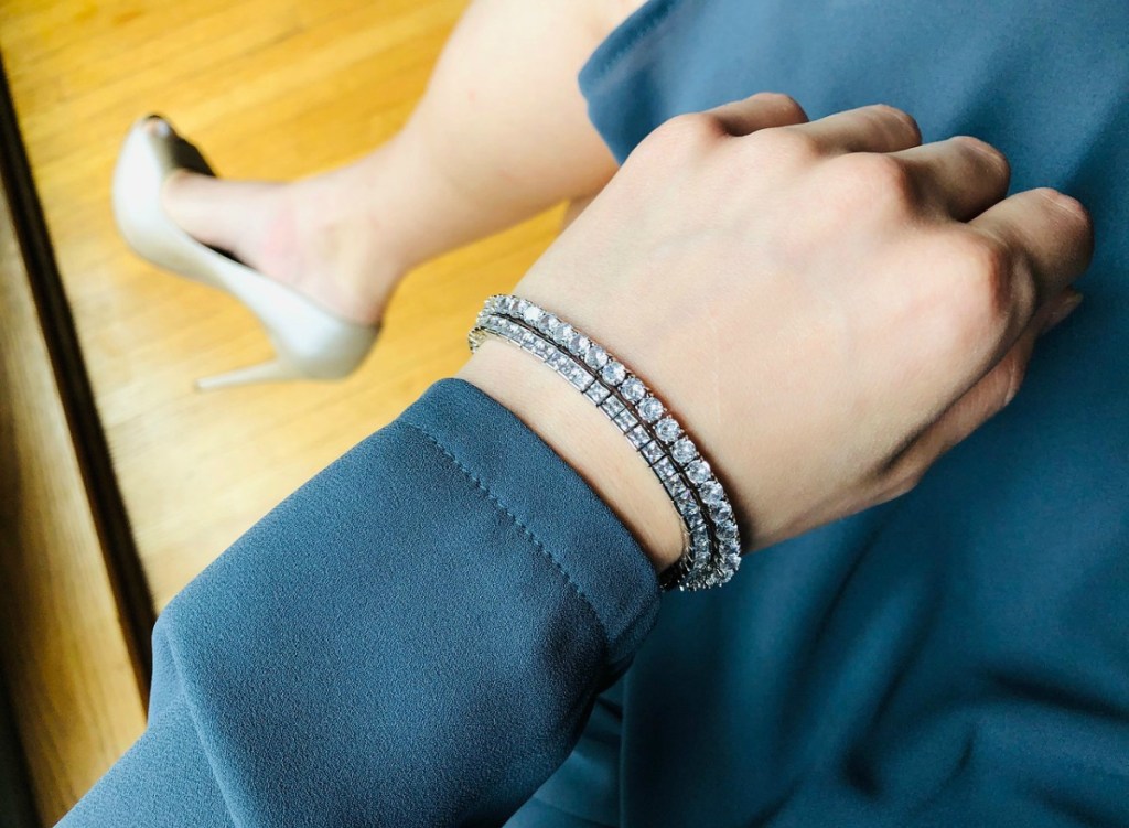woman in blue dress showing off sparkly bracelets
