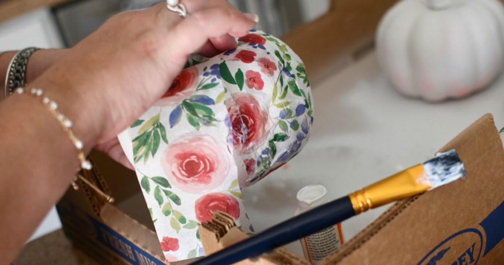 gluing strips of tissue paper to pumpkins