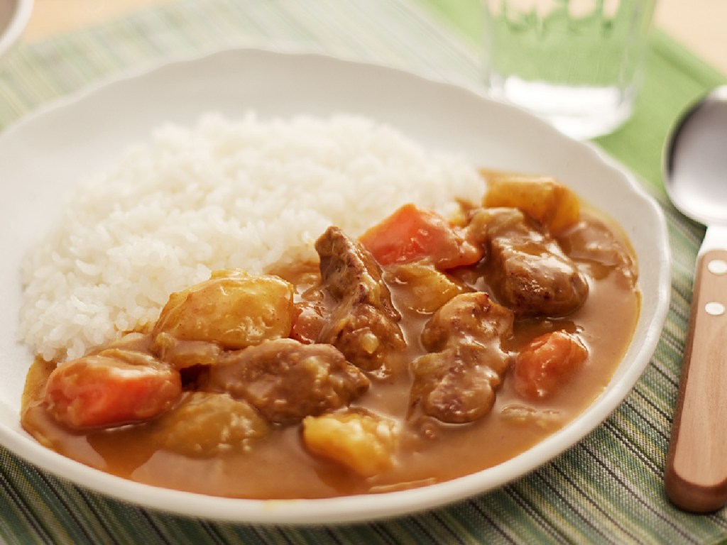 plate with beef stew one one side and rice on the other