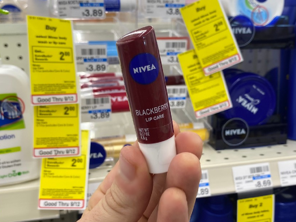 hand holding small container of lip moisture product by store display