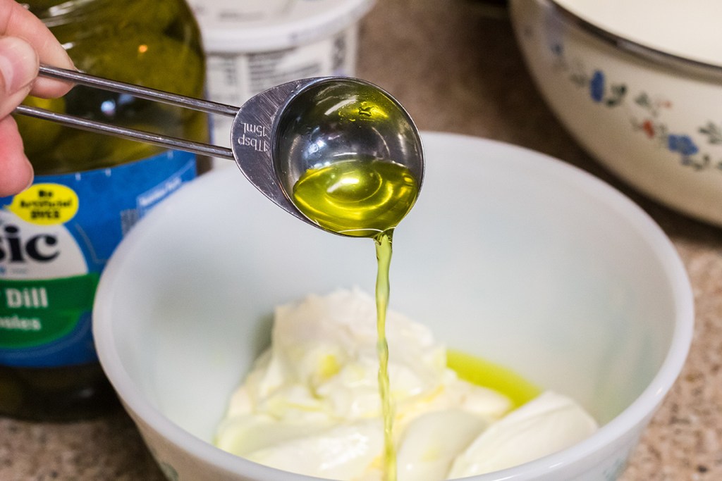 pickle juice pouring into dressing for dill pickle salad