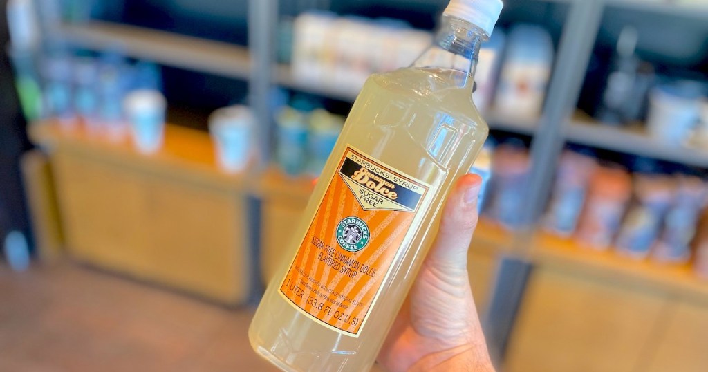 hand holding starbucks syrup in front of shelves