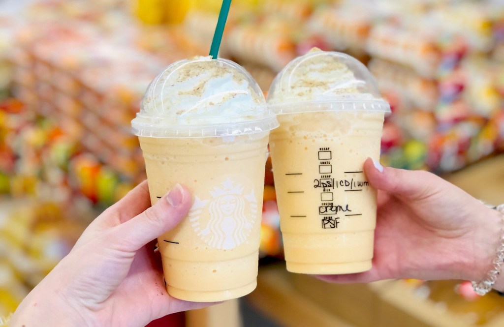 two hands holding up starbucks pumpkin frappuccino drinks
