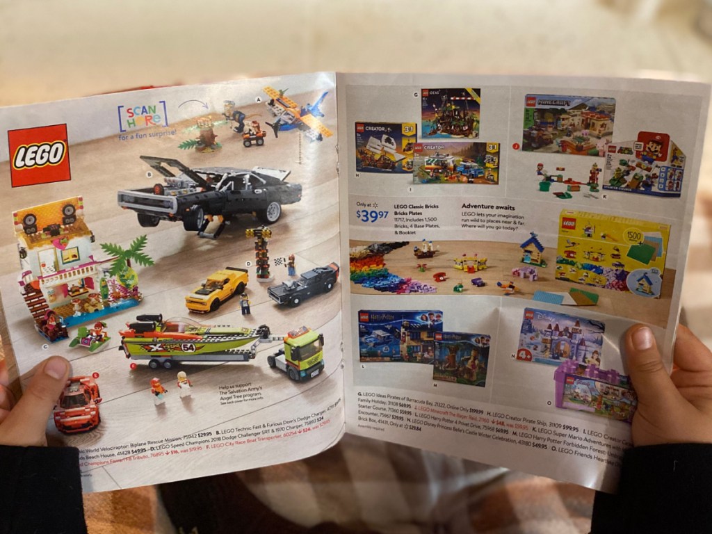 child holding the walmart 2020 toy catalog open to a lego page