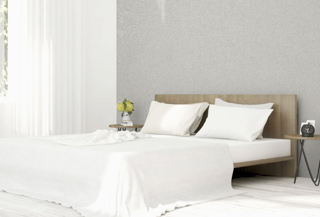 light grey textured wallpaper on wall behind bed with white linens