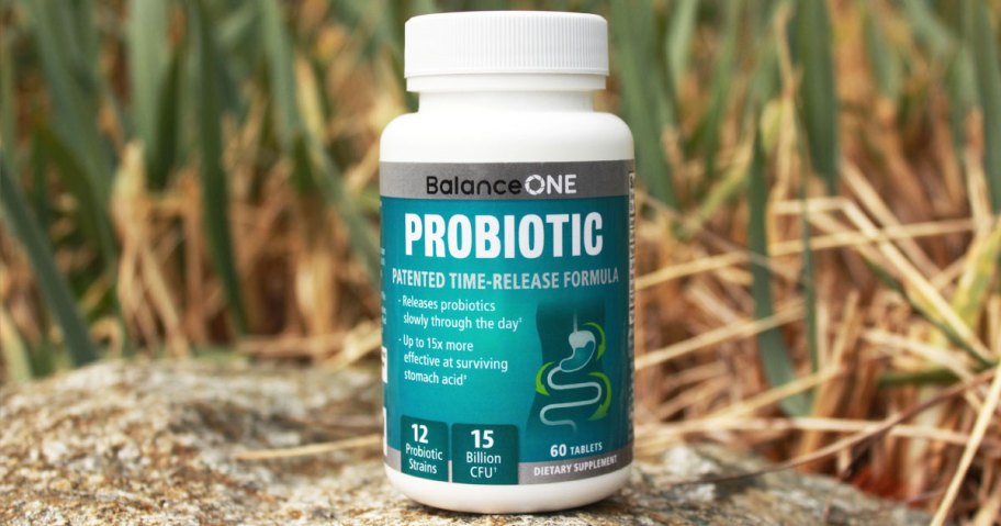 bottle of Balance ONE Probiotics on a rock near grass